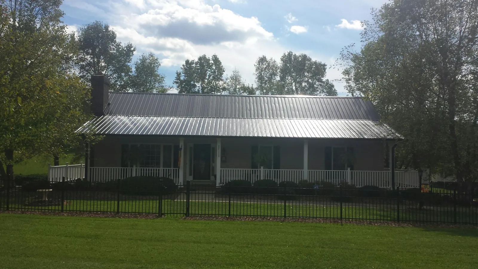 Gray metal roof on a brick ranch with a full width front porch — Gutter Guard Installation work by our crew in Friendship